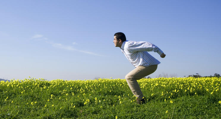 man getting ready to jump into the air in the middle of a field of yellow flowers