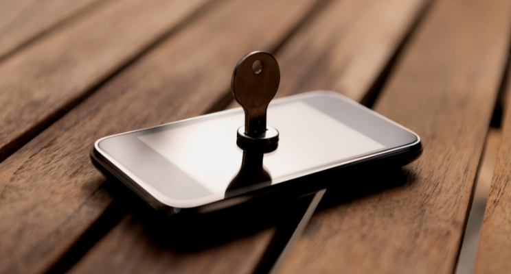 key placed on top of a smartphone on wooden table