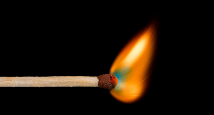 close up of a lit match against black background