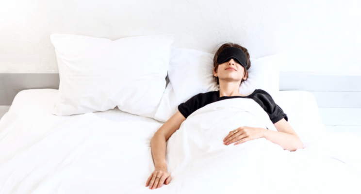 a woman in bed with black eye mask on
