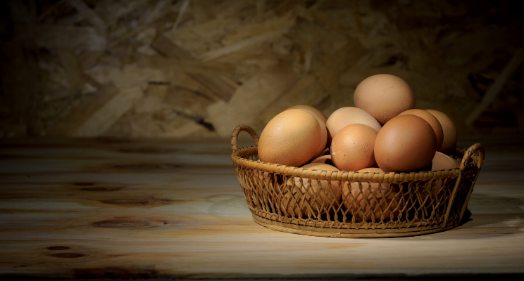 several eggs in a wicker basket on a wooden table