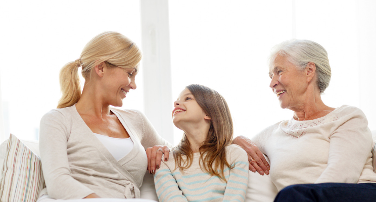 multigenerational women sitting and smiling on a couch