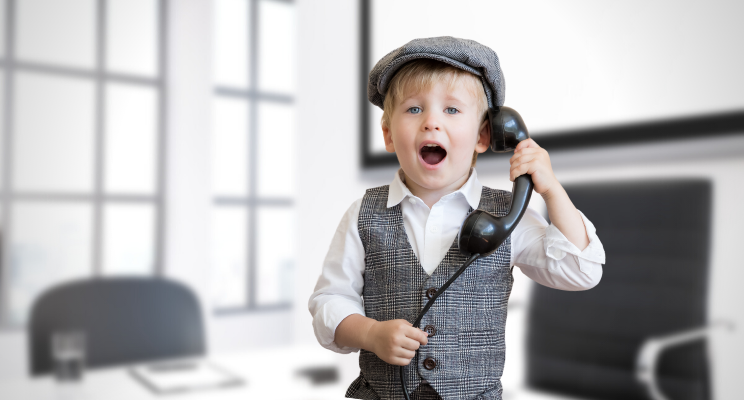 young child holding a cord telephone in an office setting